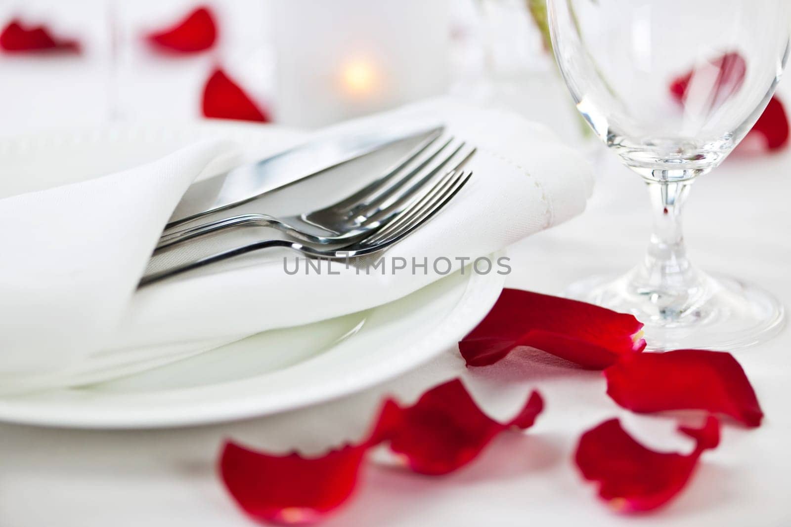 Romantic table setting with rose petals plates and cutlery