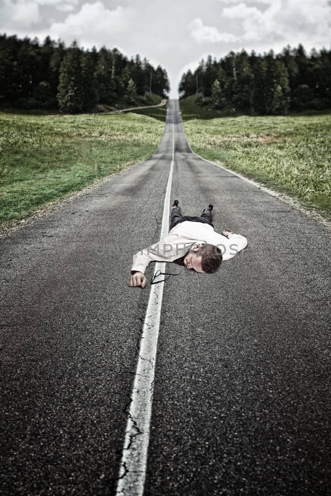 businessman lying down on long road