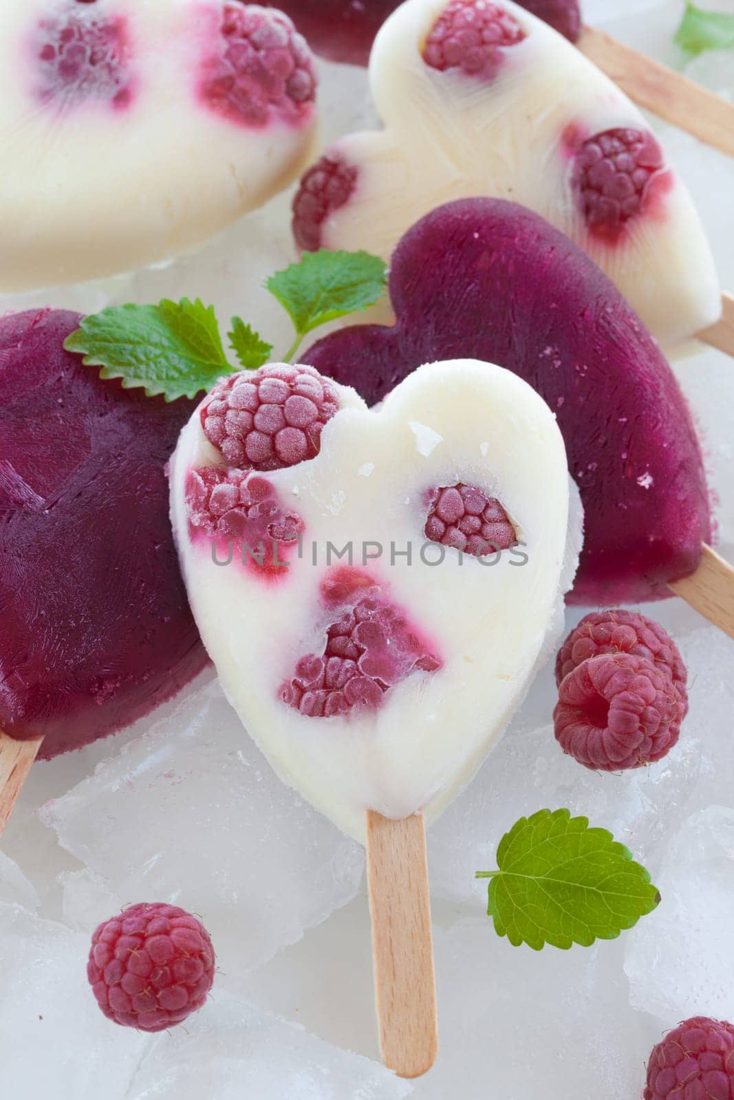 Ice cream on the stem in heart shape with fresh raspberries