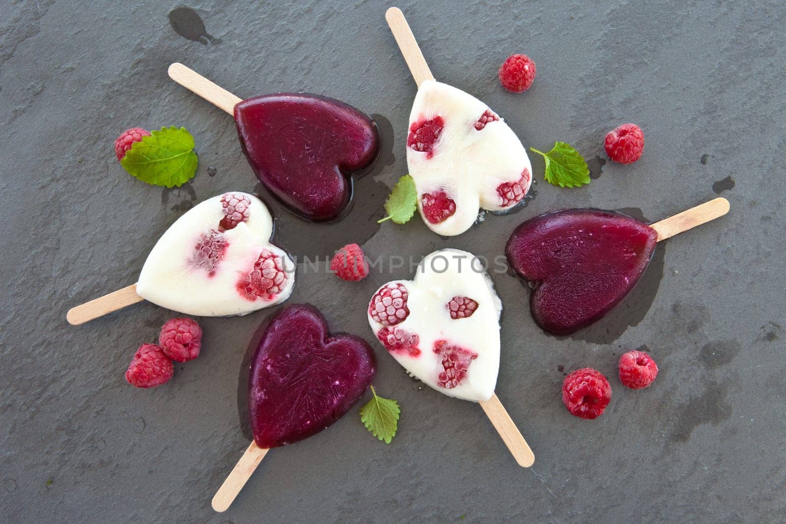 Ice cream on the stem in heart shape with fresh raspberries