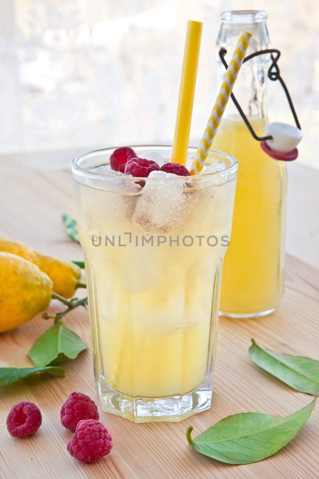 Cold lemonade with fresh lemons and raspberries
