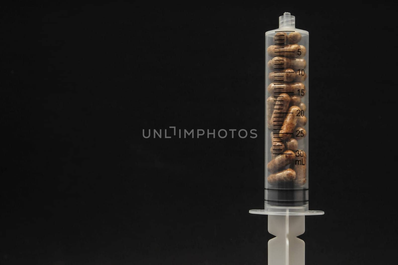 Medical Syringe Full of Pill Drugs on a Black Background