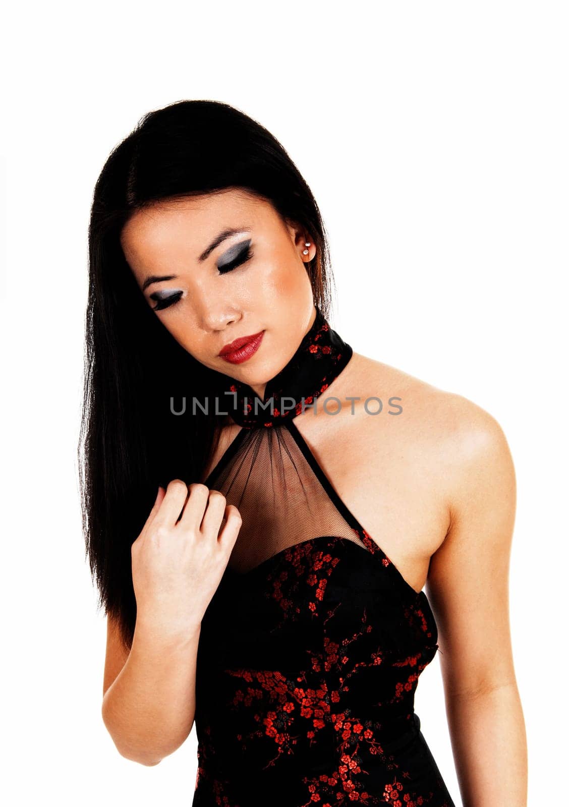 A young Chinese woman with long black hair wearing a black-red dress .standing for white background with her eye's closed..