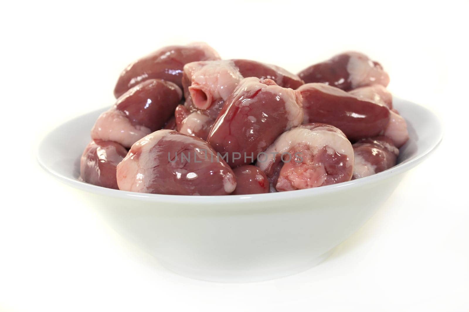 fresh raw chicken hearts against a white background