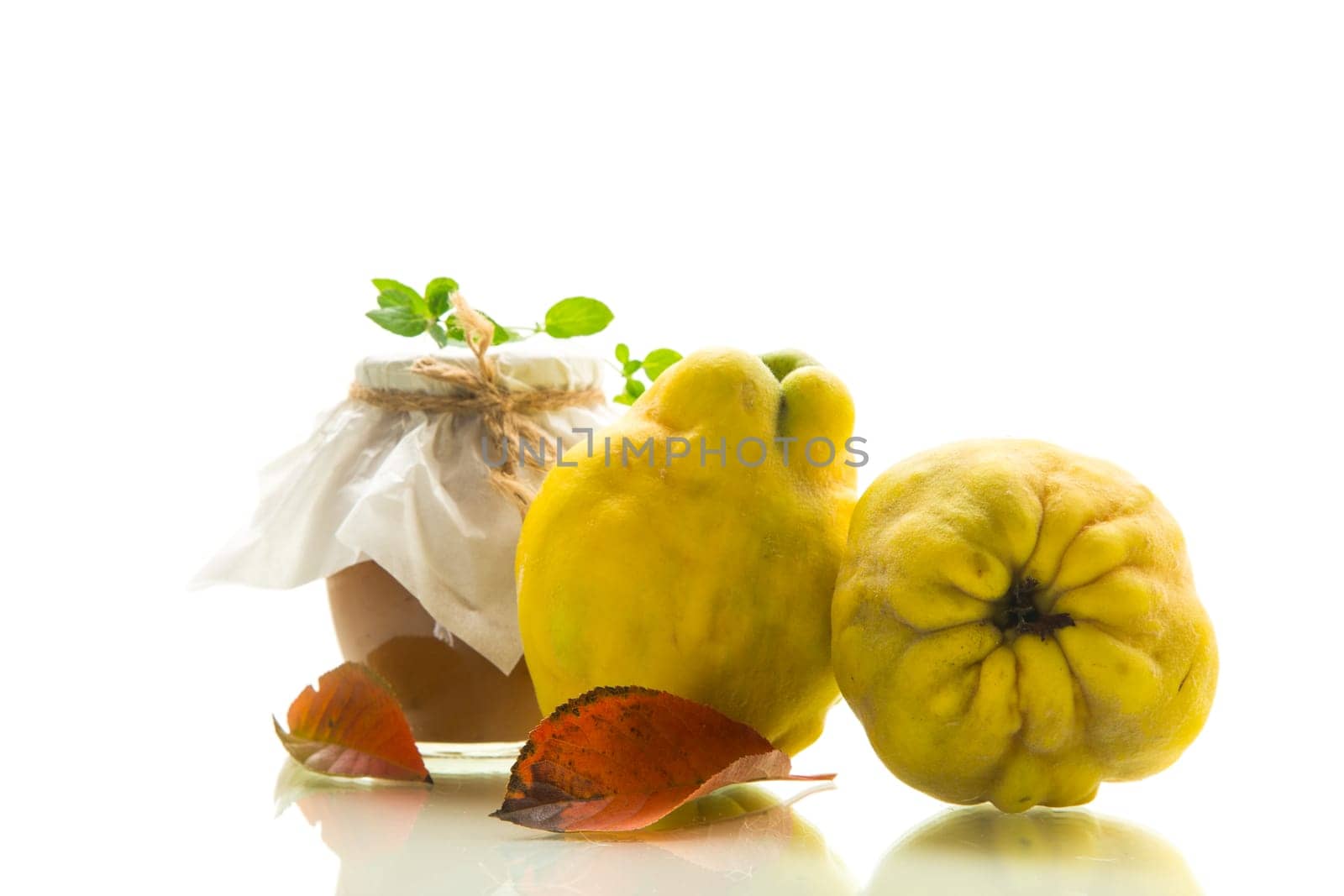 Ripe quince fruit with jam in a glass jar isolated on a white background. Autumn recipes.