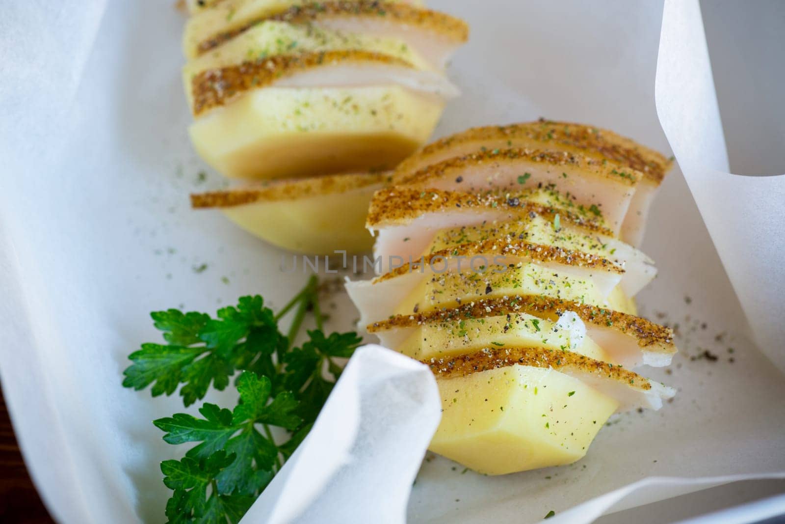 Raw potatoes stuffed with lard and spices, prepared for baking in baking paper.