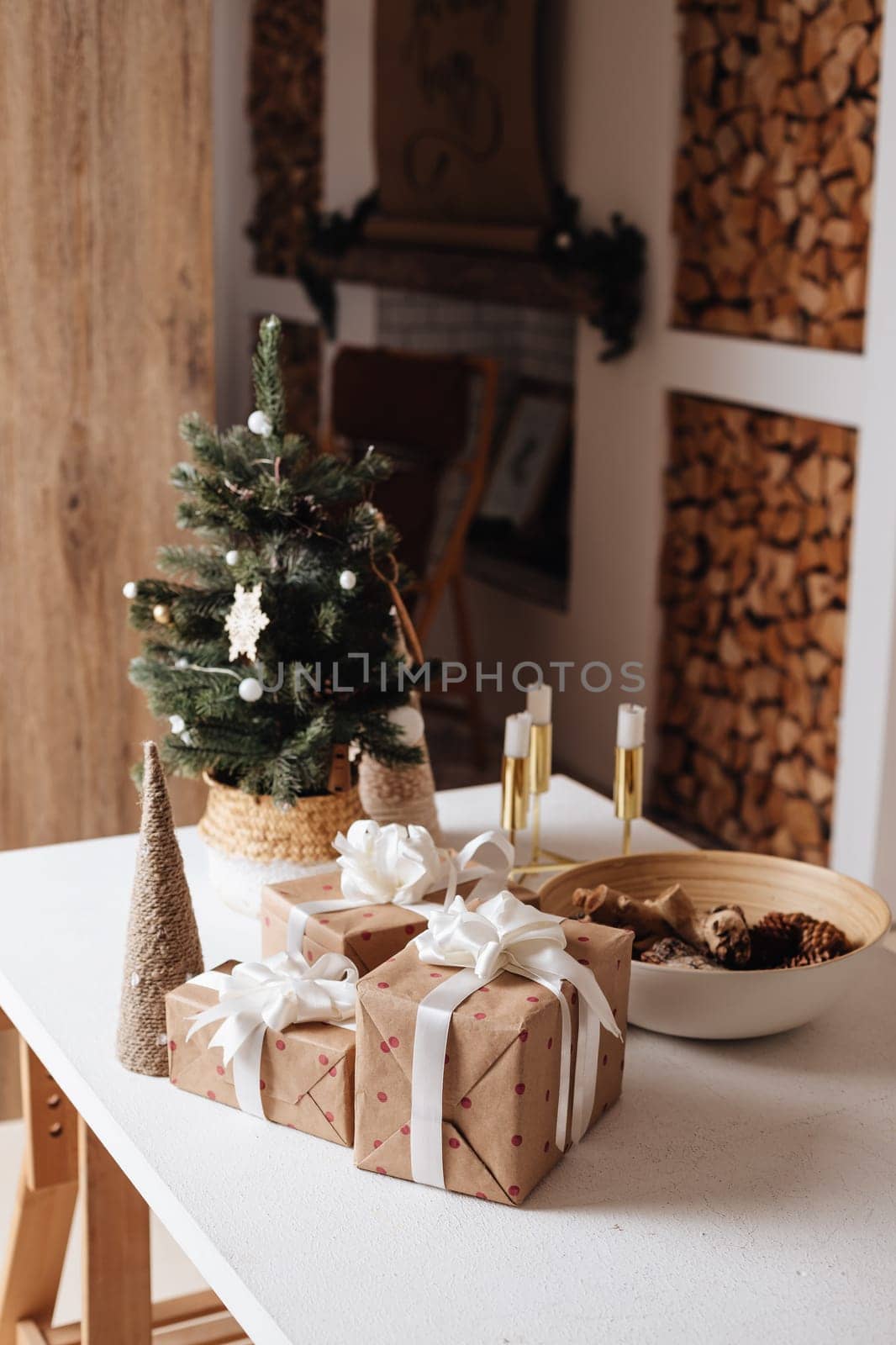 Wrapped in golden paper present boxes on table closeup and veautiful holdiay decorated christmas tree with ornaments and garland unfocused. Winter holiday background