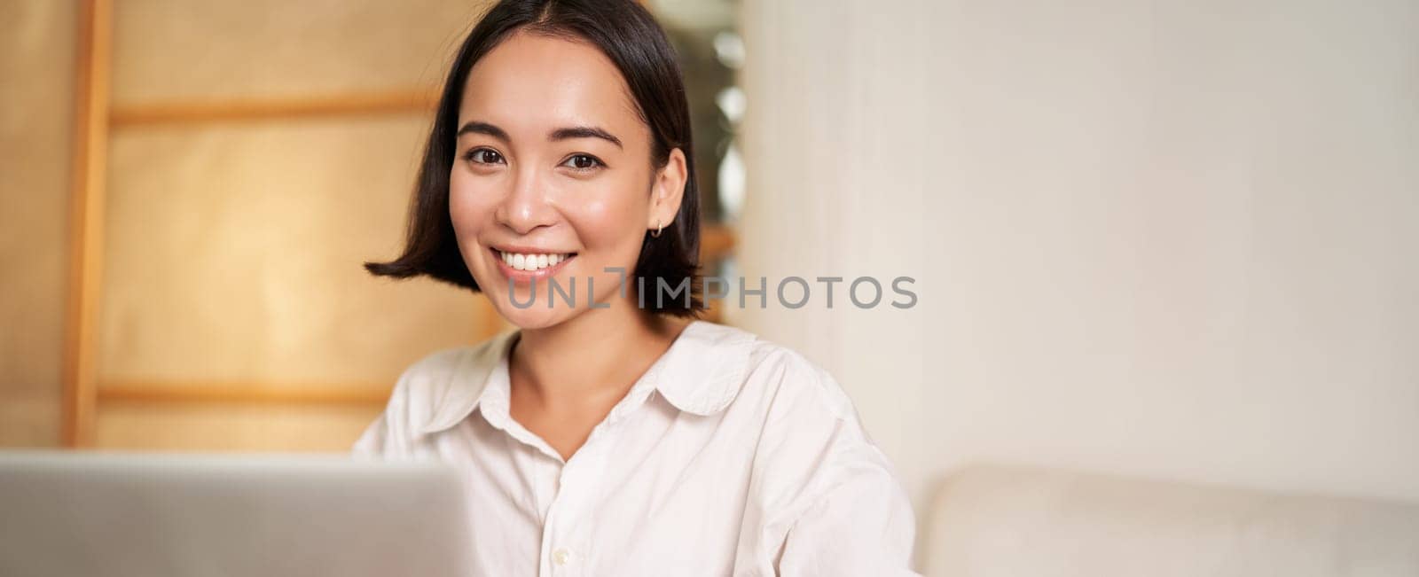 Stylish brunette woman with laptop, sitting in cafe and drinking coffee, smiling happily. People and lifestyle concept