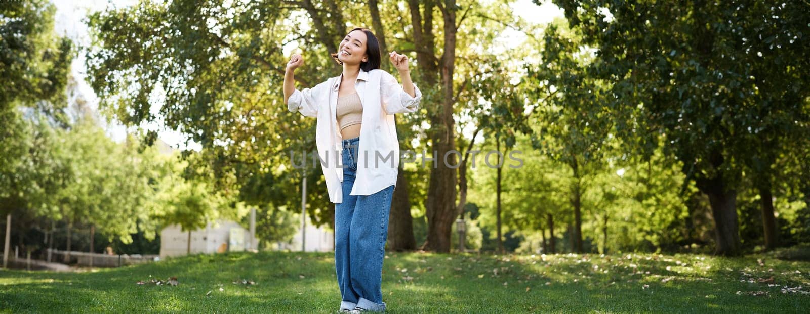 Portrait of happy girl dancing and looking happy, posing in park, enjoying herself, walking alone, feeling freedom and excitement by Benzoix