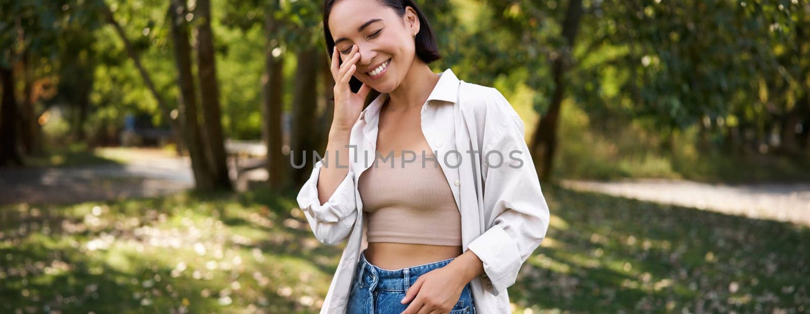 Stylish asian girl walks in park, laughs and enjoys summer weather. People and lifestyle concept by Benzoix