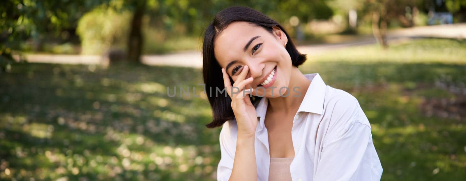 Beautiful young asian girl smiling, laughing and walking along park, enjoying summer sunny day. People and lifestyle concept
