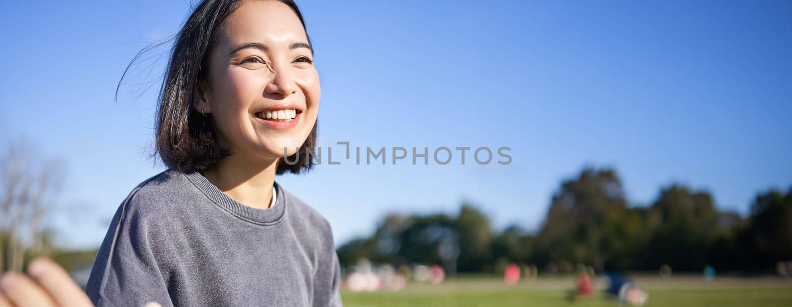 Vertical shot of happy korean girl sitting in park, learning how to play ukulele, singing and relaxing by Benzoix