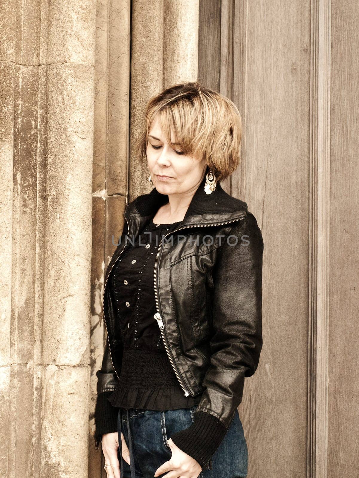 woman looking thoughful leaning against stone pillar
