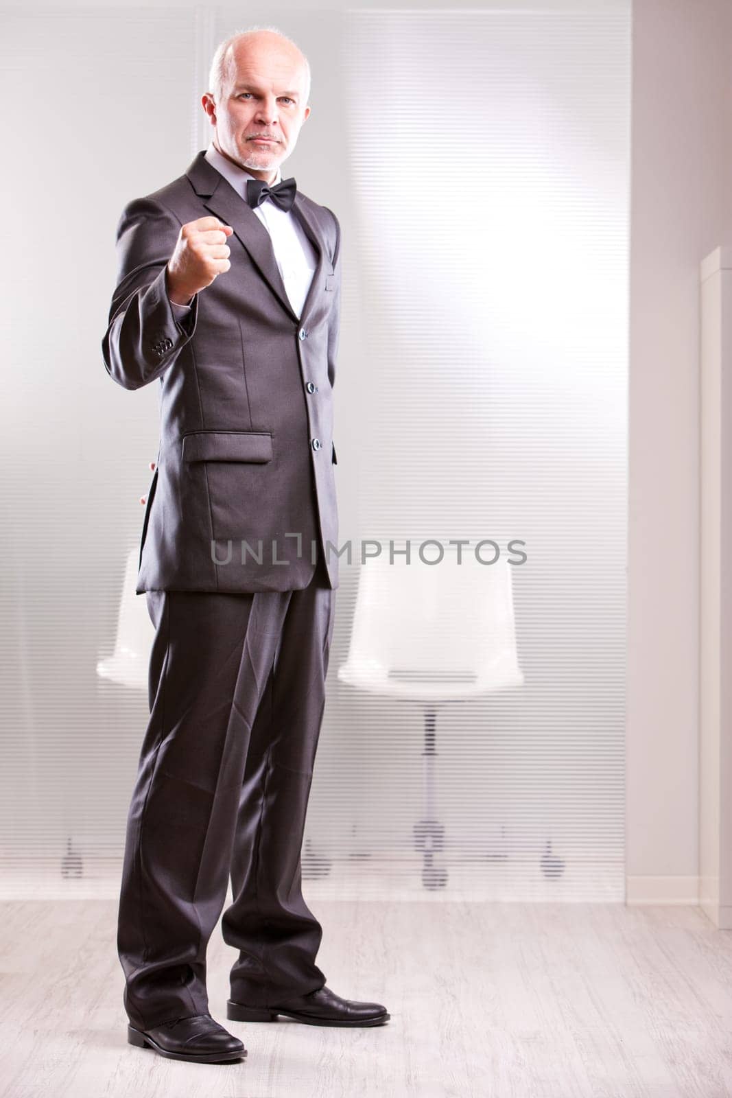 strong middle aged businessman looking at you with his fist rased looking at you as a colleague