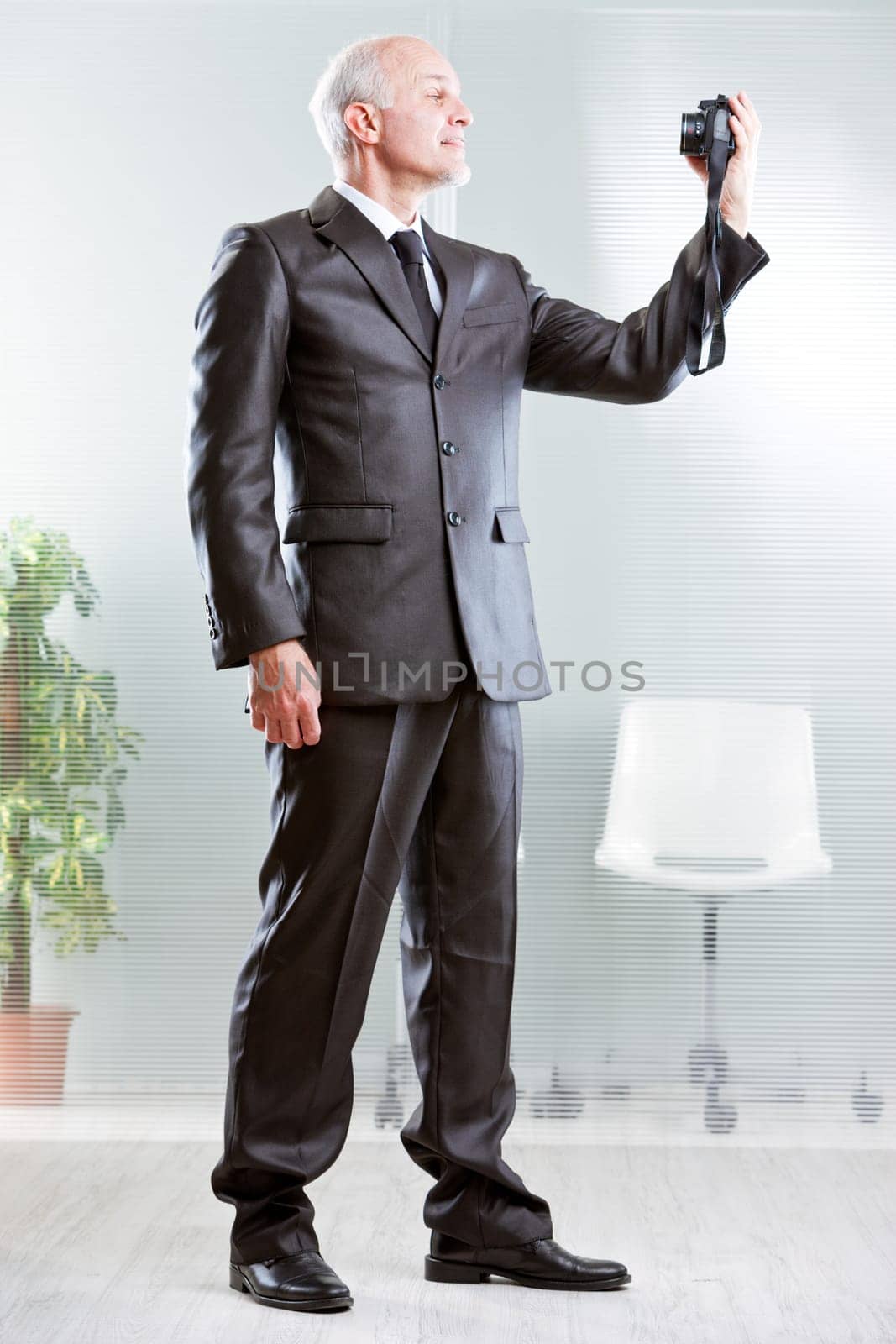 Strong standing businessman making a selfie with his digital camera