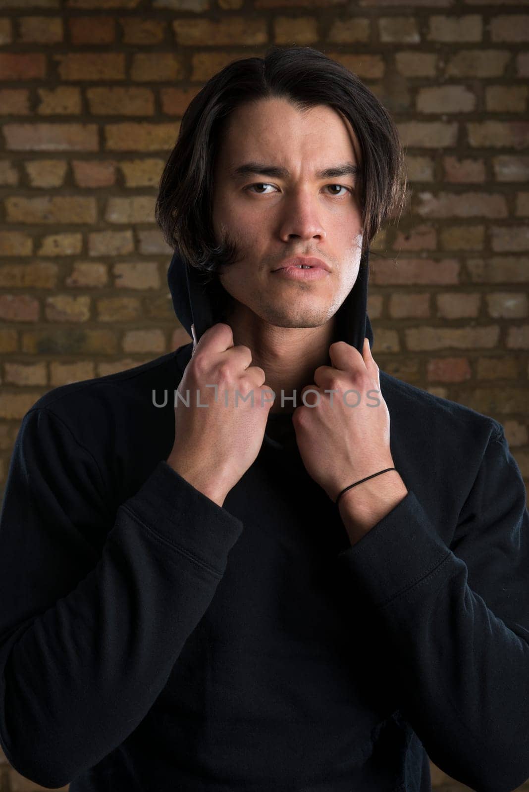 Portrait of handsome Malaysian man wearing hoodie and looking serious