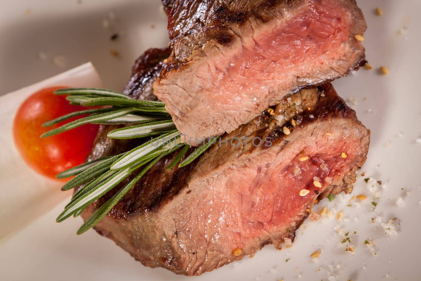 Medium fried beef steak fillet with pepper and rosemary sliced on a plate