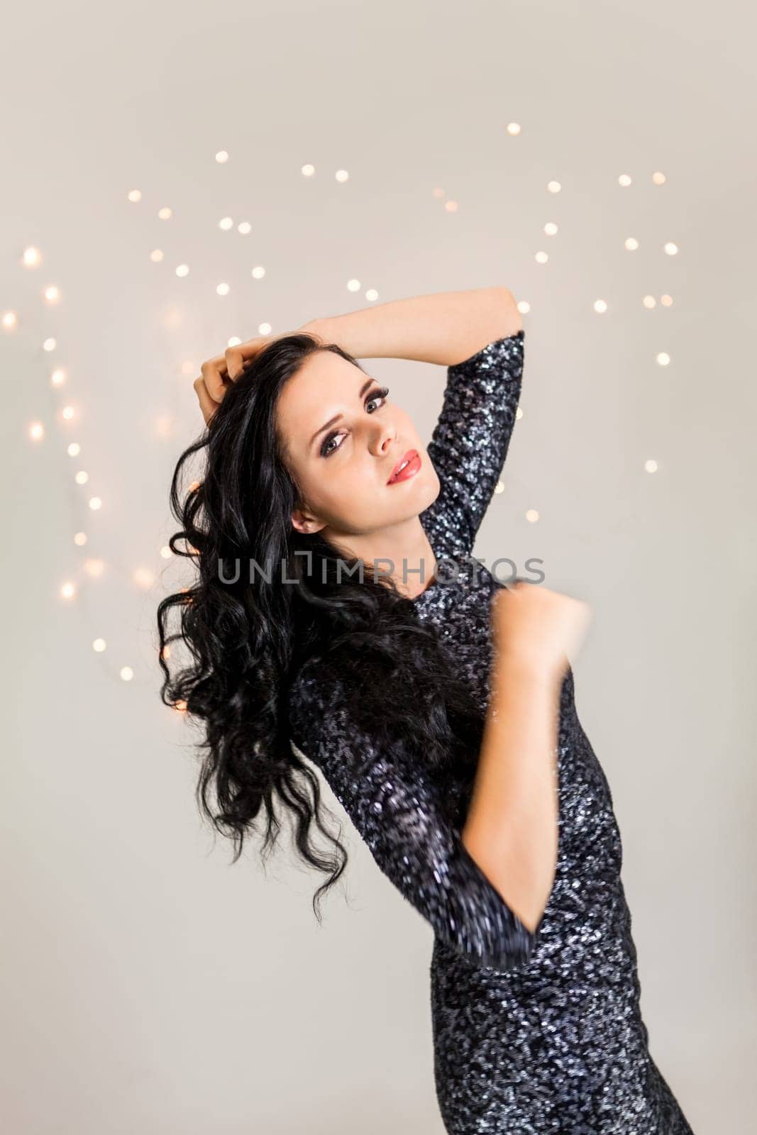 attractive young dark haired woman with evening wardrobe at dancing party holiday glitter dress bokeh