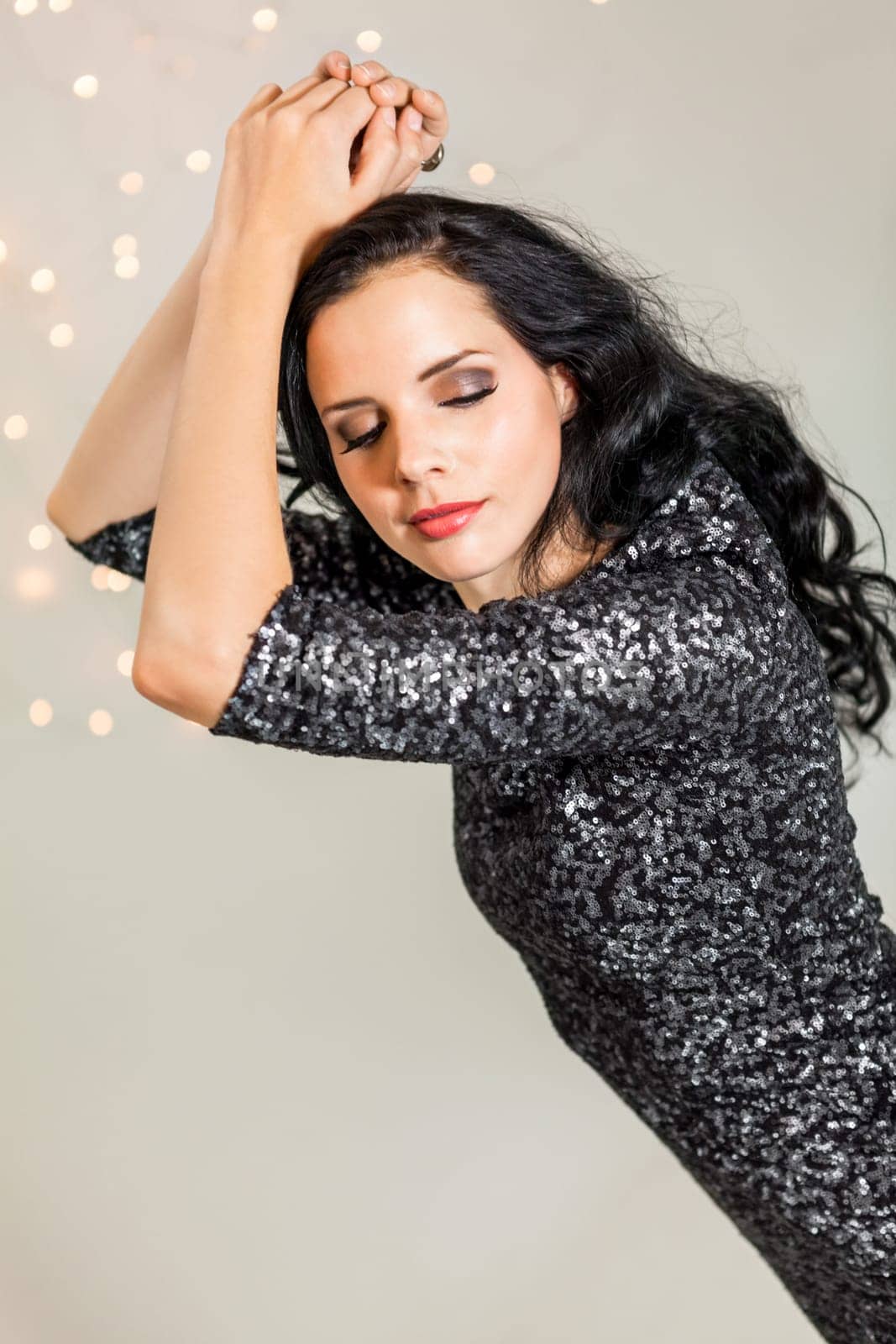 attractive young dark haired woman with evening wardrobe at dancing party holiday glitter dress bokeh