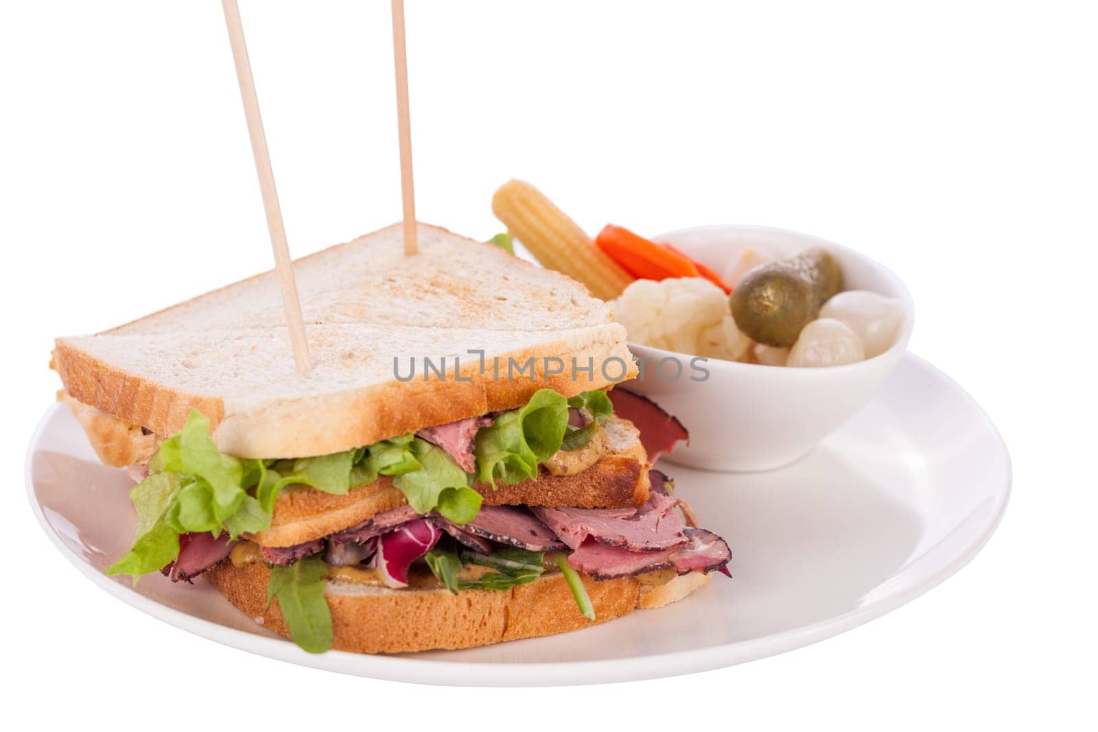 Delicious sandwich clubsandwich with bacon ham cheese and one with mixed pickels on a plate isolated against a white background