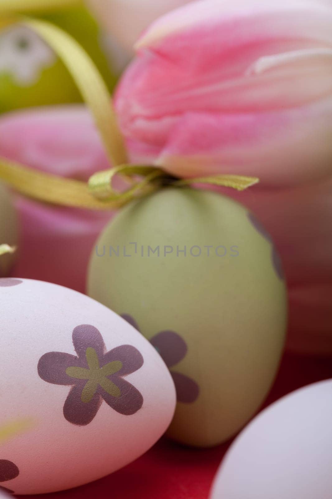 pink tulips decorated with easter eggs as a close-up with text space on a red background