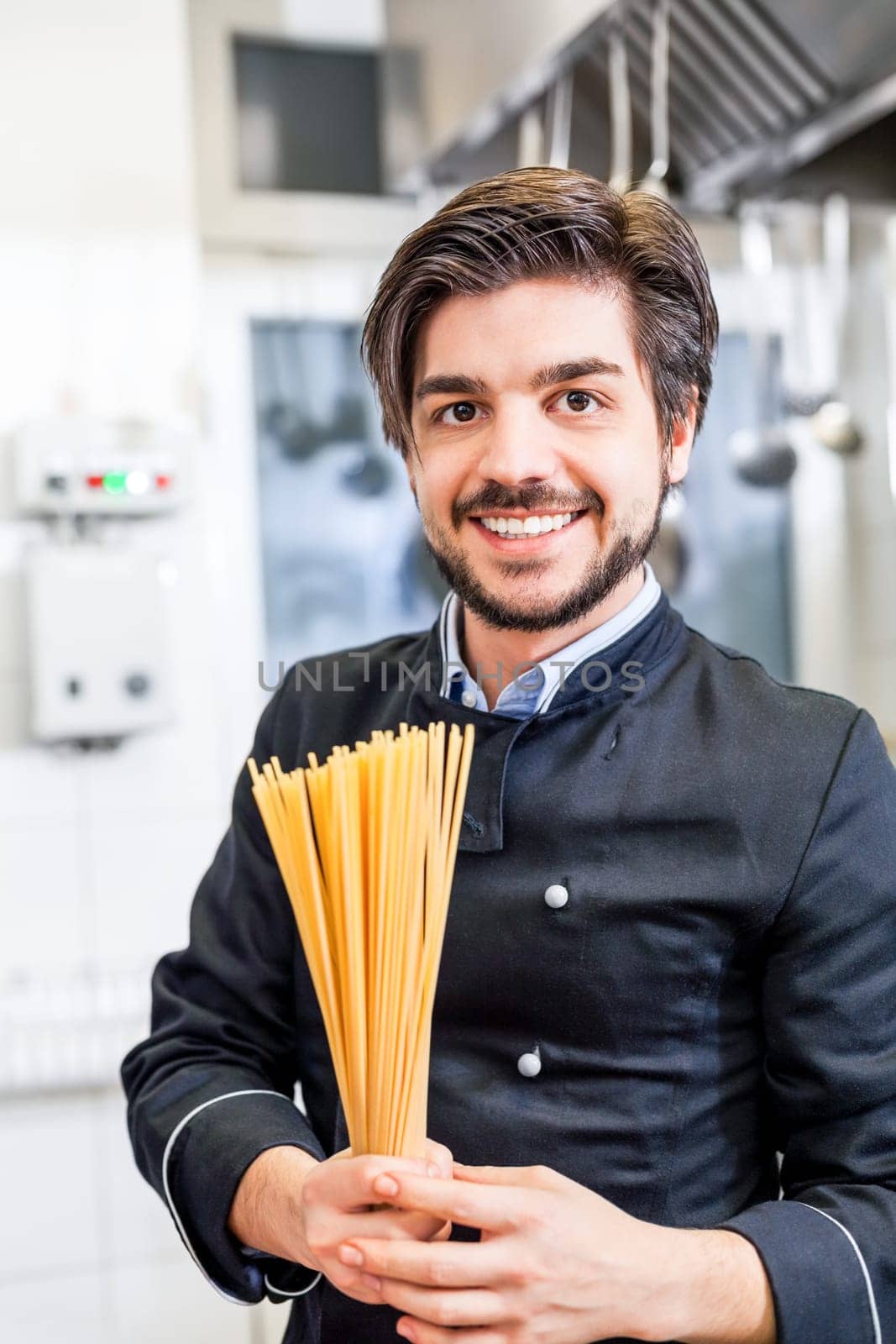 young chef prepares fresh Italian pasta spaghetti at the herd in the restaurant kitchen too