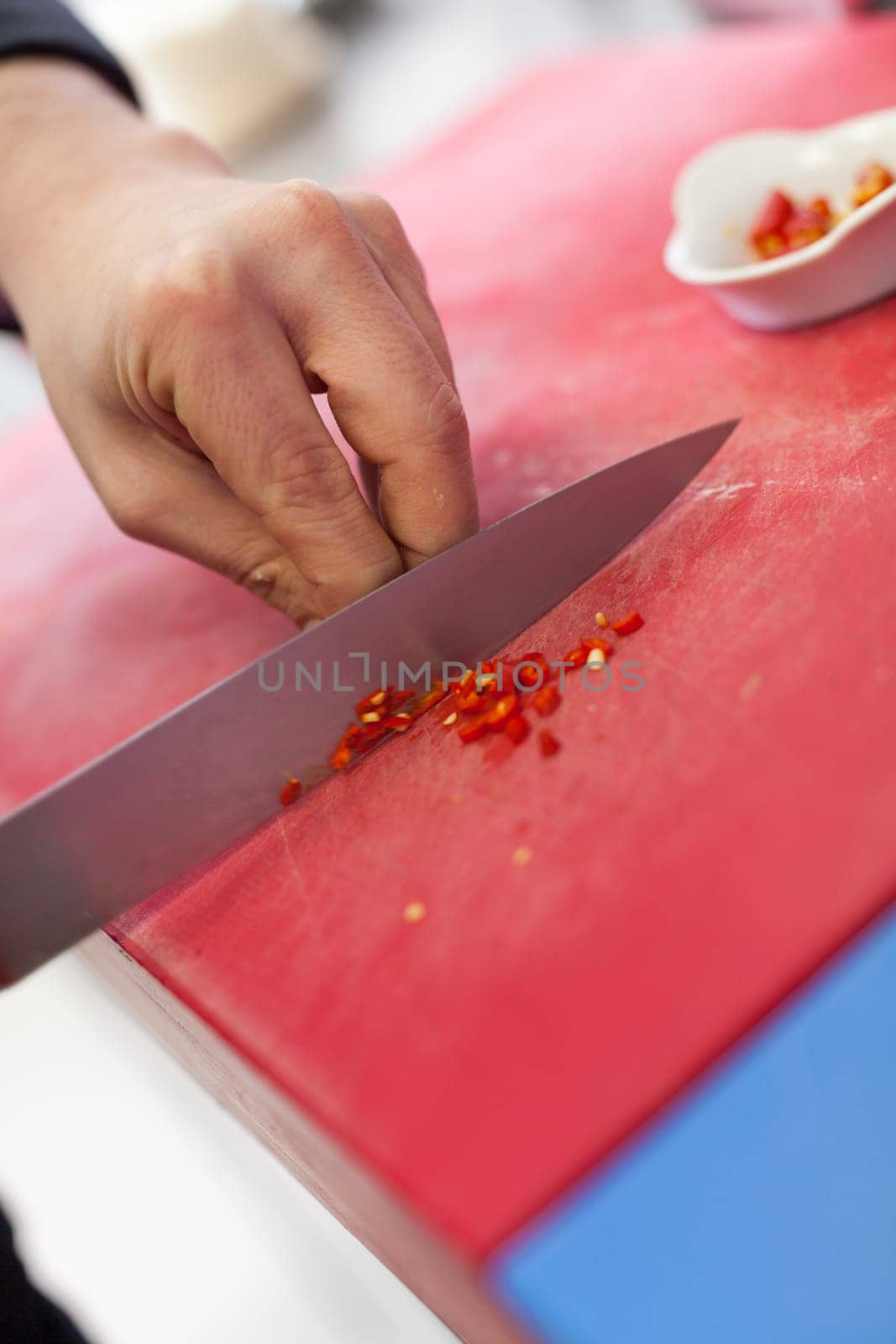 chef cuts fresh red chilli small in the restaurant kitchen to eat gatsronomie food