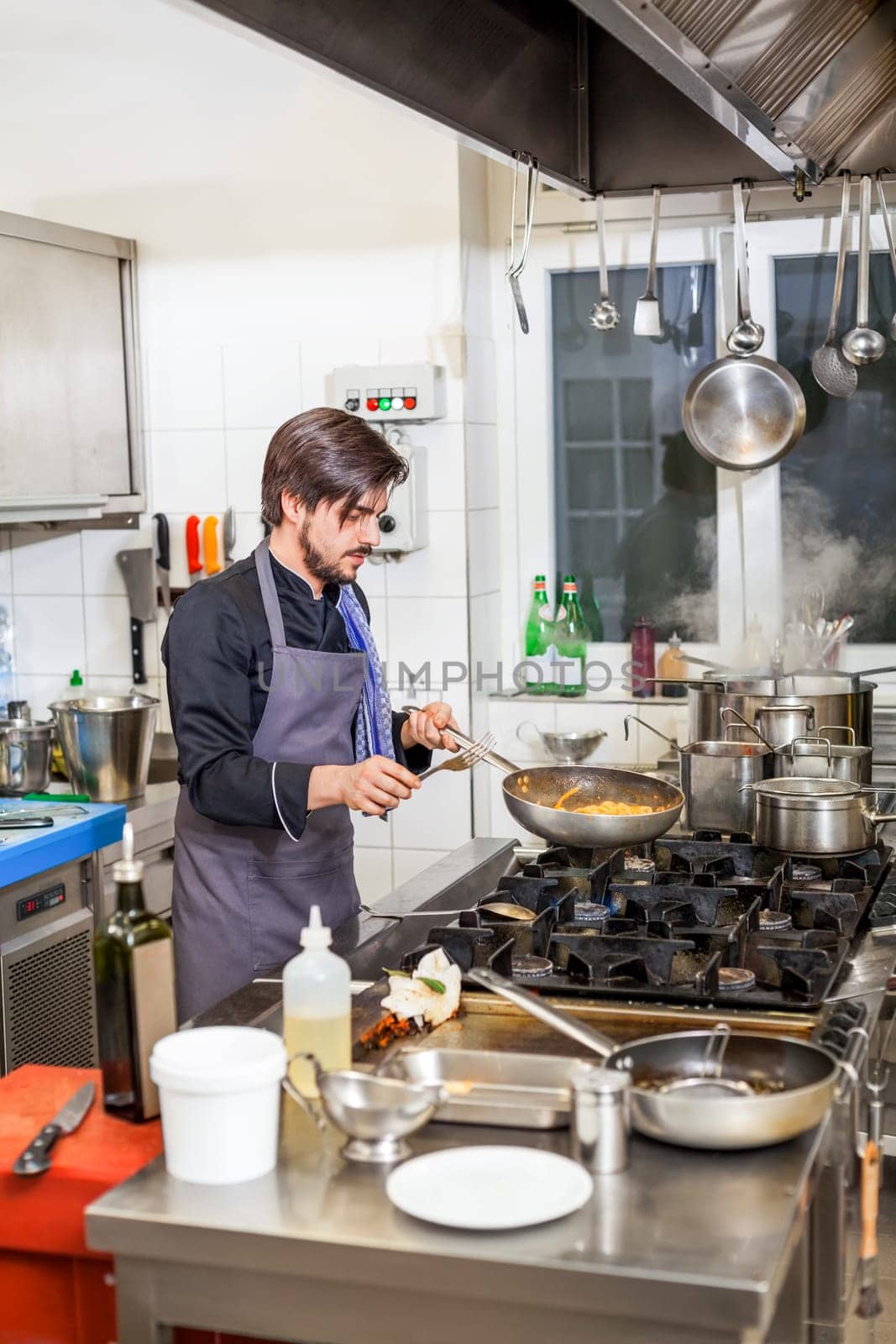 young adult chef in the restaurant kitchen while cooking at the herd preparation