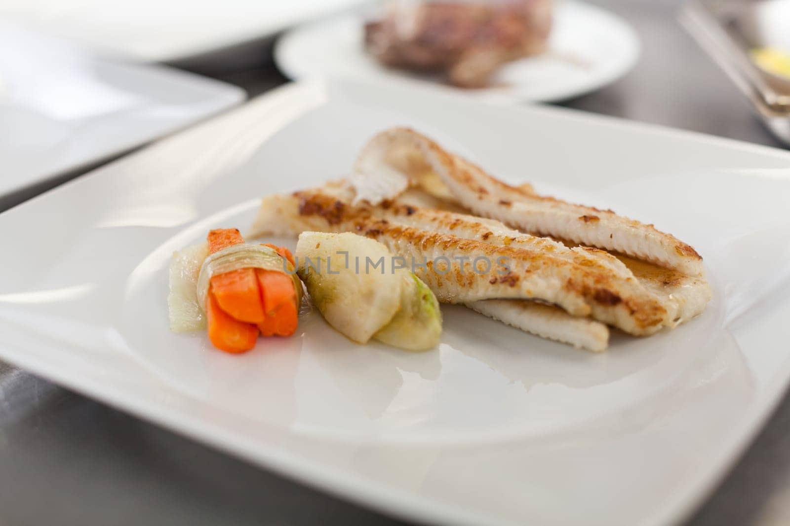 fresh fried fish fillet with vegetables and sauce on a teller restaurant kitchen preparation dinner