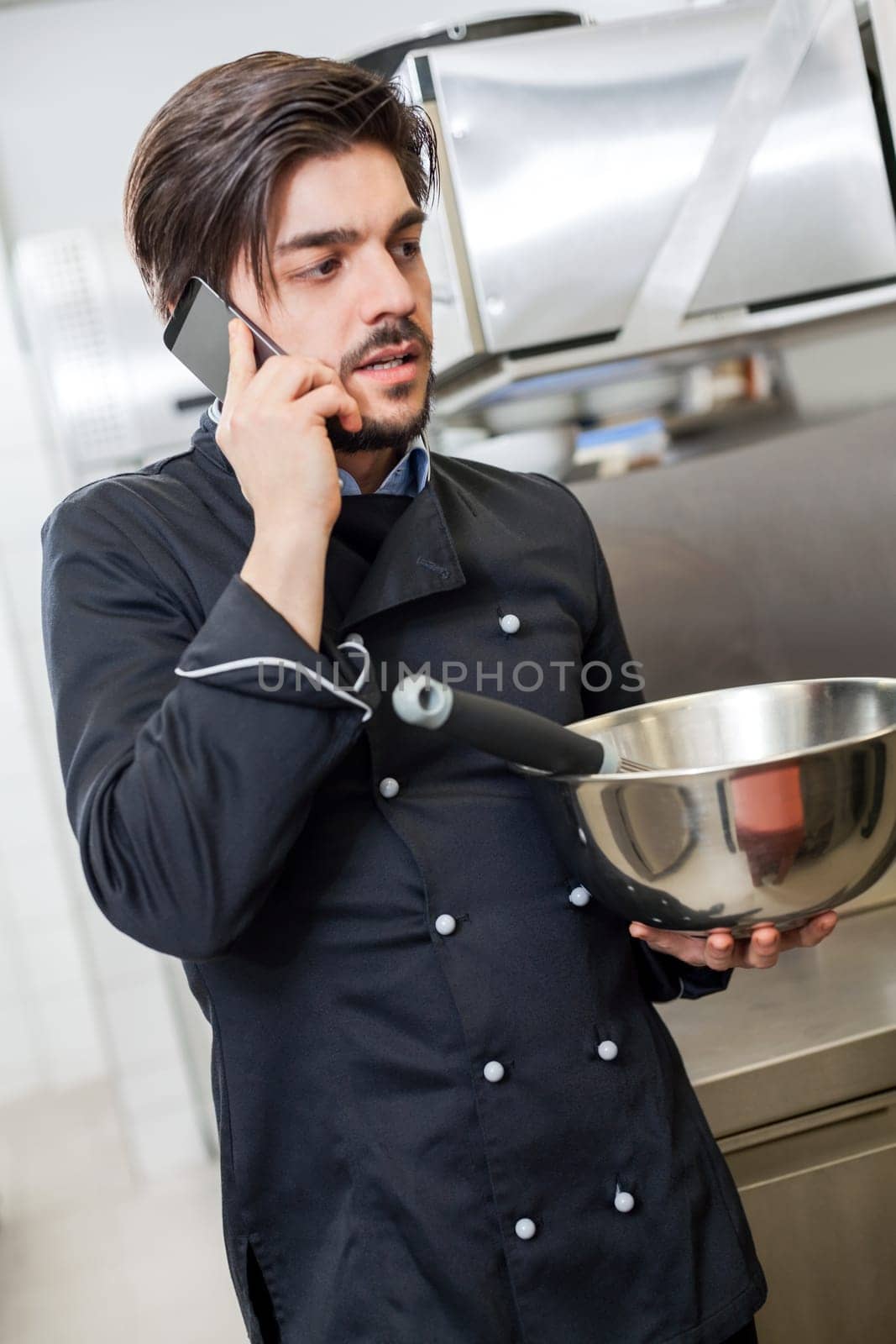 young chef on the phone while cooking in the restaurant kitchen work success stress communication