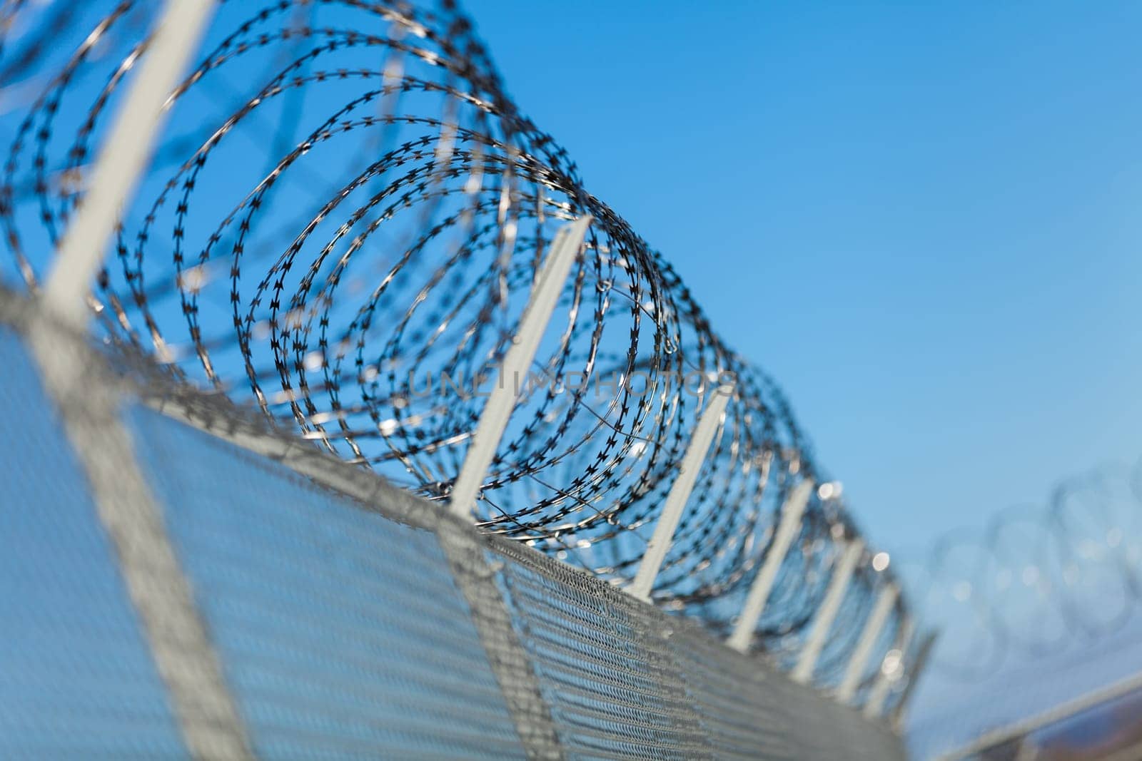 barbed wire fence outdoors in front of blue sky macro close-up detail