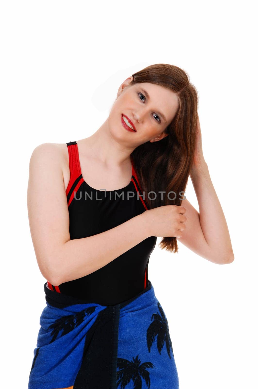 A lovely young woman in a black bathing suit standing from the front.fixing her hair for white background..
