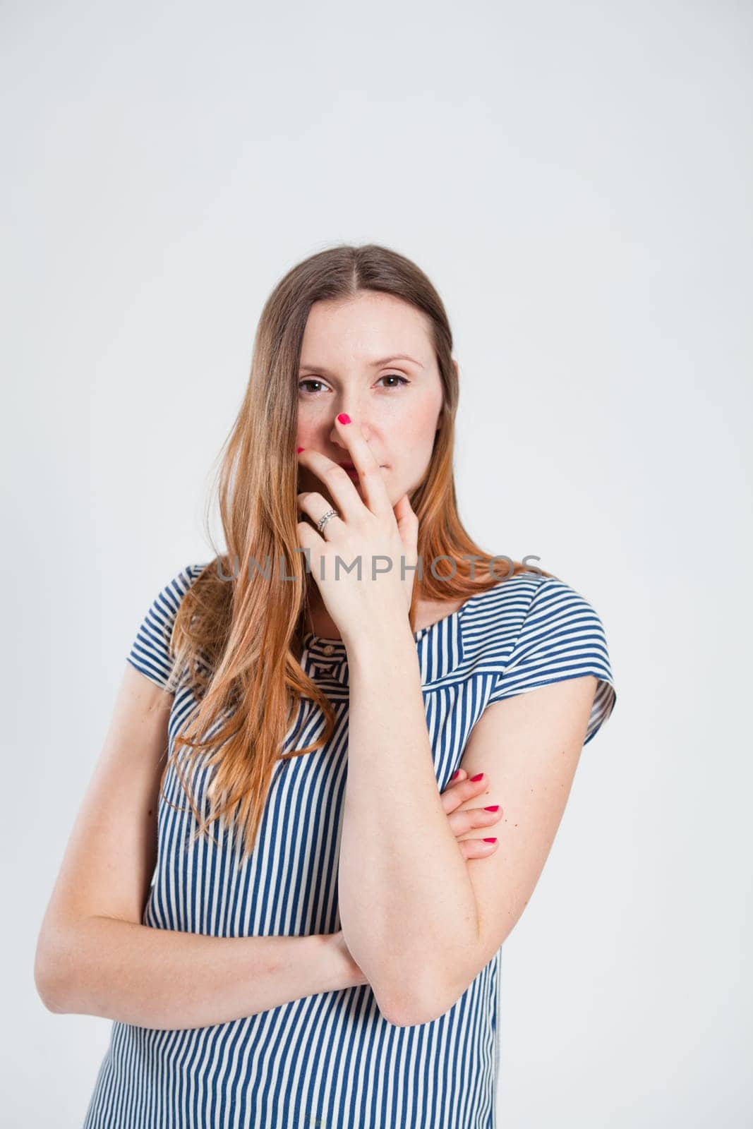 Studio portrait of relaxed attractive and stylish woman touching lower part of face with hand