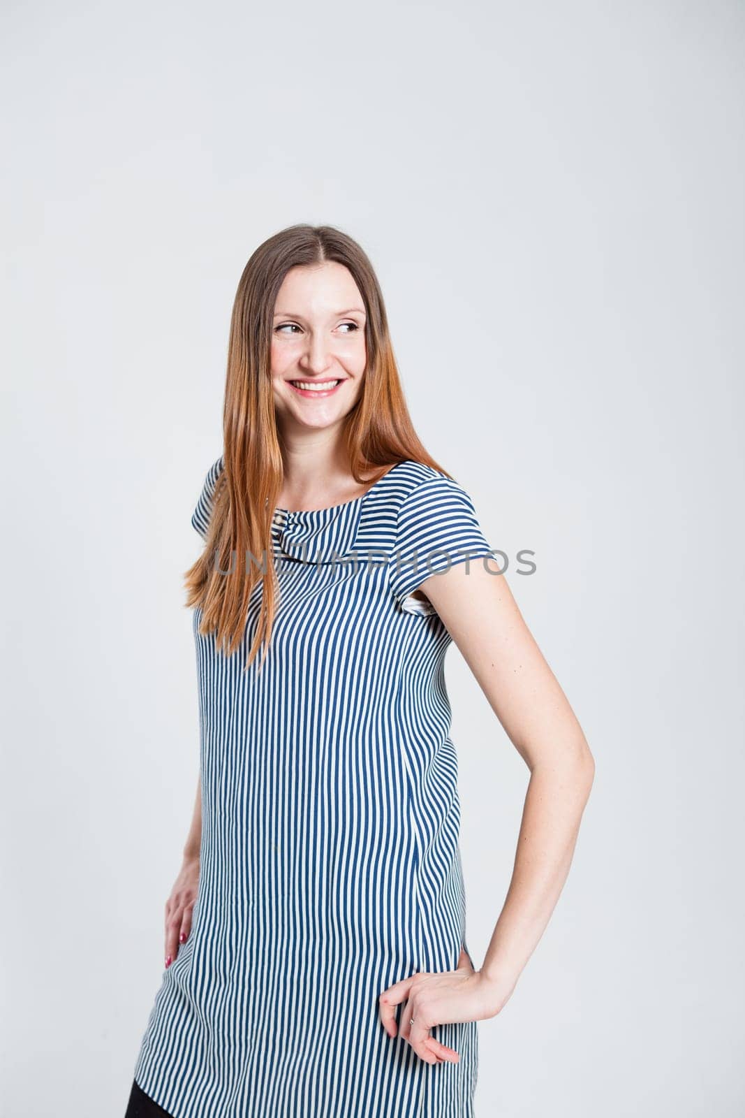 Studio portrait of smiling attractive and stylish woman posing while looking to side