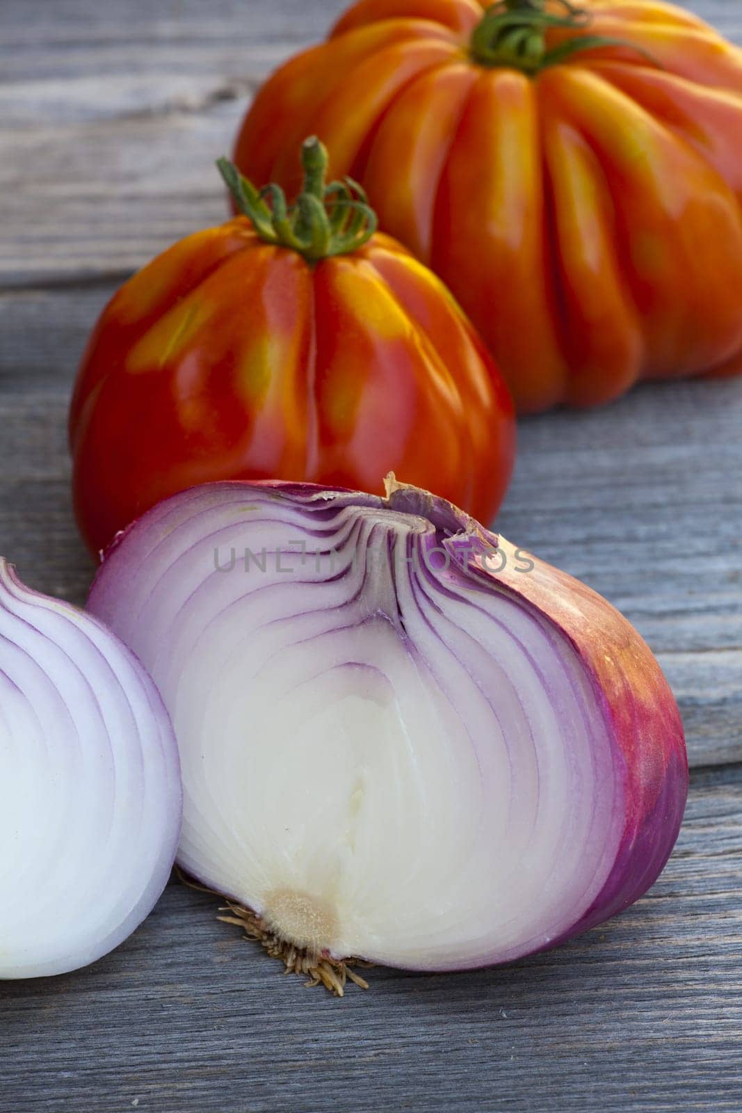Coeur de Boeuf Tomatoes and large red Onions from Weekly Market in South France on a old wooden Table