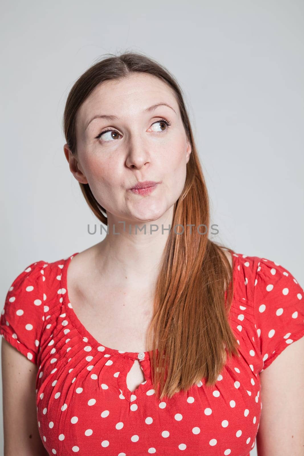 Studio portrait of thoughtful looking attractive woman with pursed lips looking to side