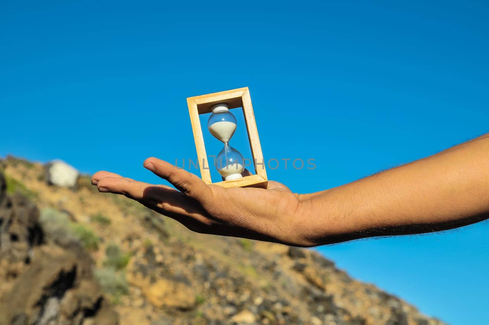 Time Concept White Sand Hourglass on the Volcanic Rocks