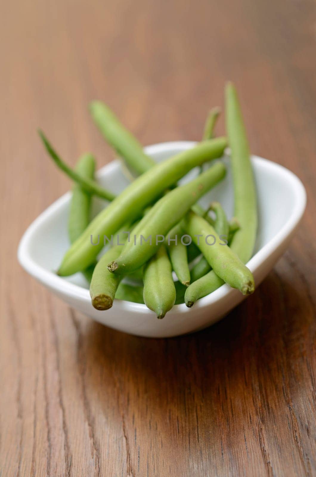 Green beans in a white bowl on a wooden table