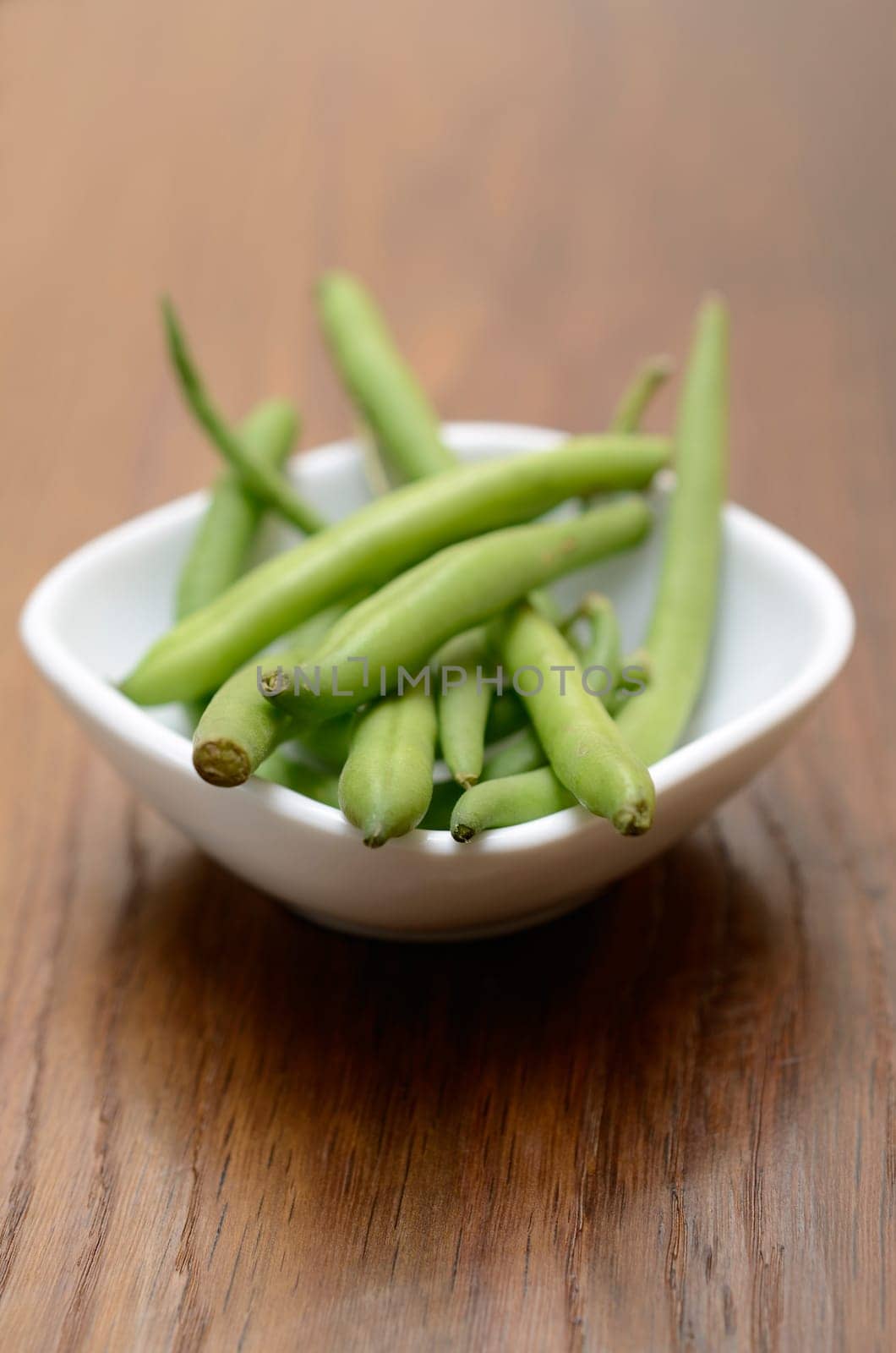 Green beans in a white bowl on a wooden table