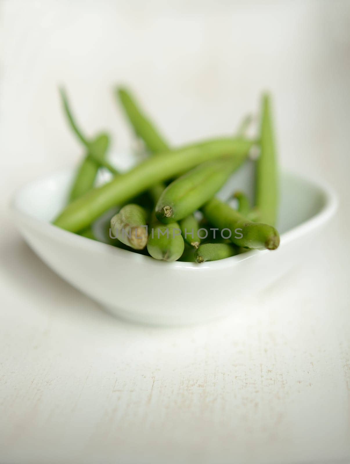Green beans in a white bowl on a wooden table
