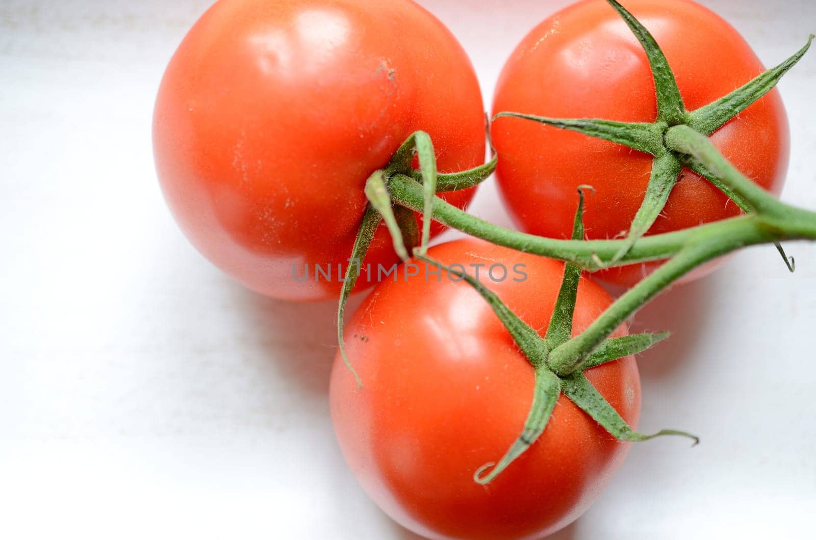 Three tomatoes on a white wooden bowl