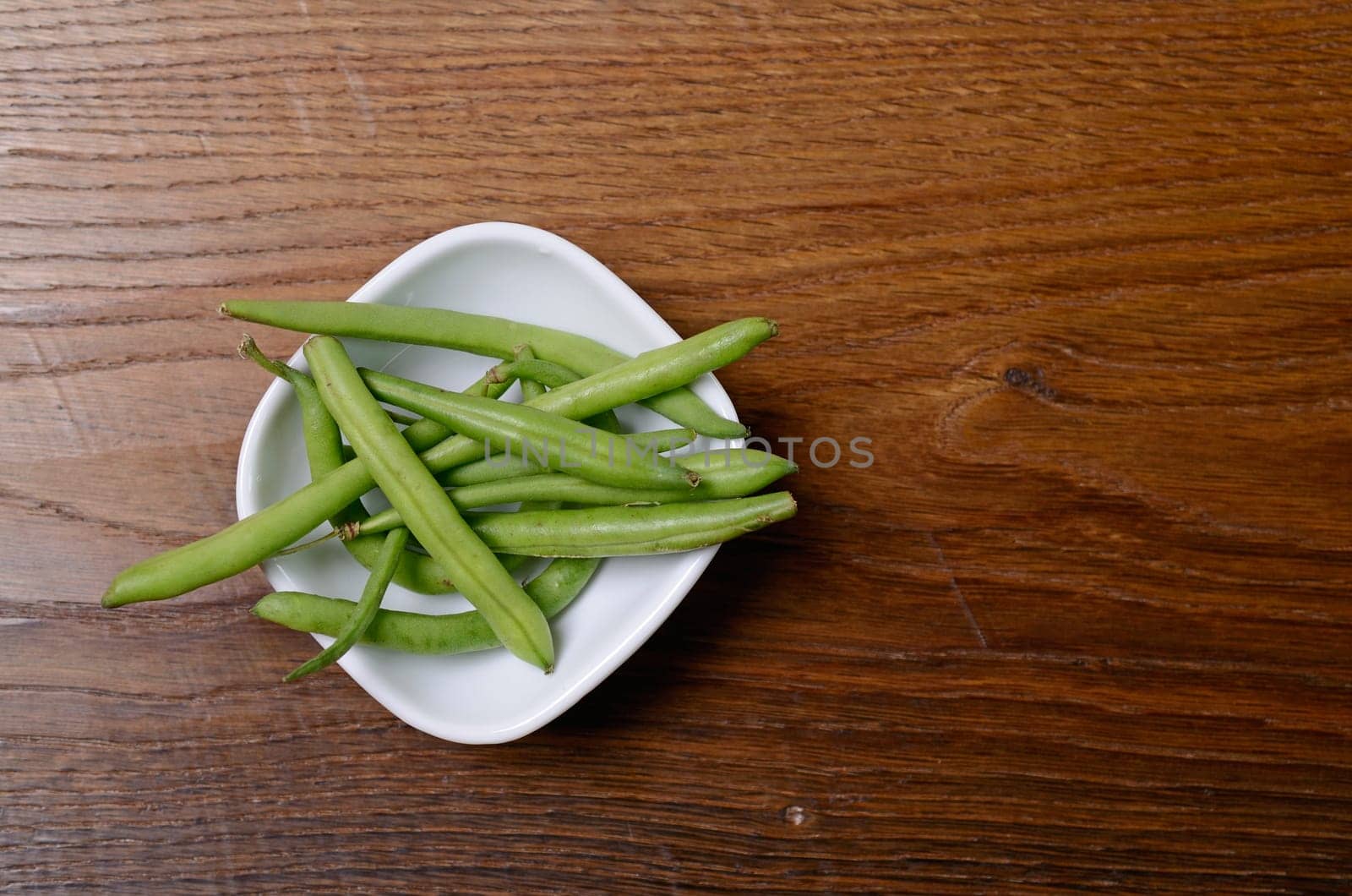Green beans in a white bowl on a wooden table