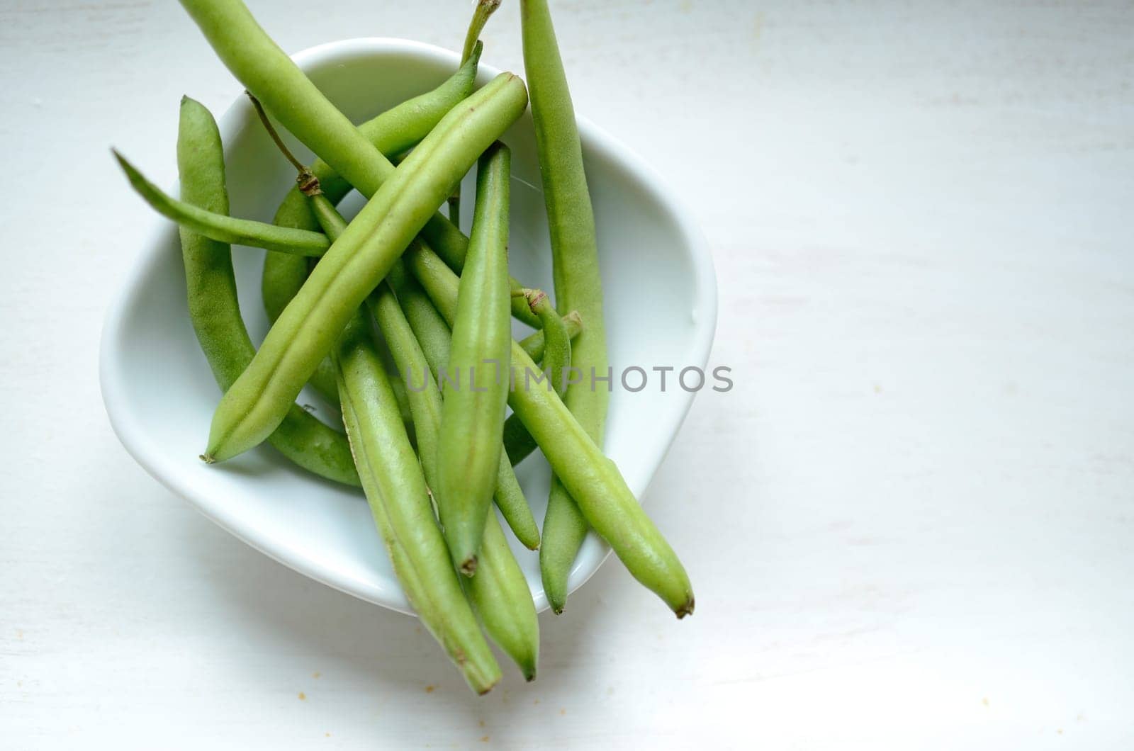 Green beans in a white bowl on a wooden table