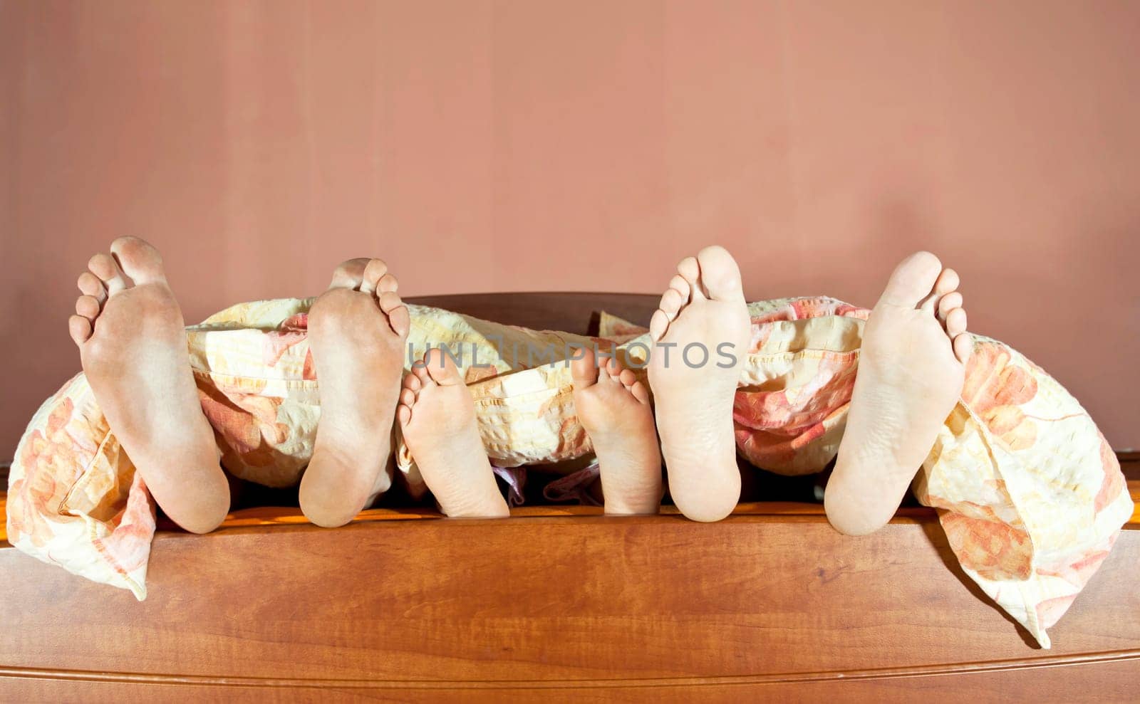 Tree pairs of legs of the happy family in bed - father, mother and child