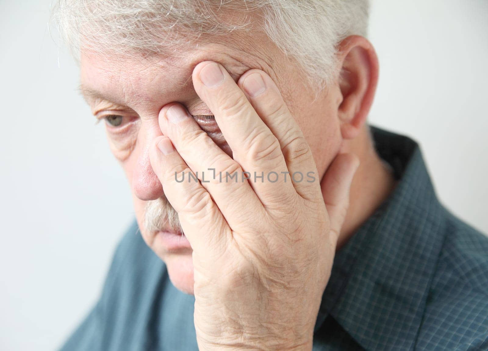 overworked senior rubs an eye in fatigue