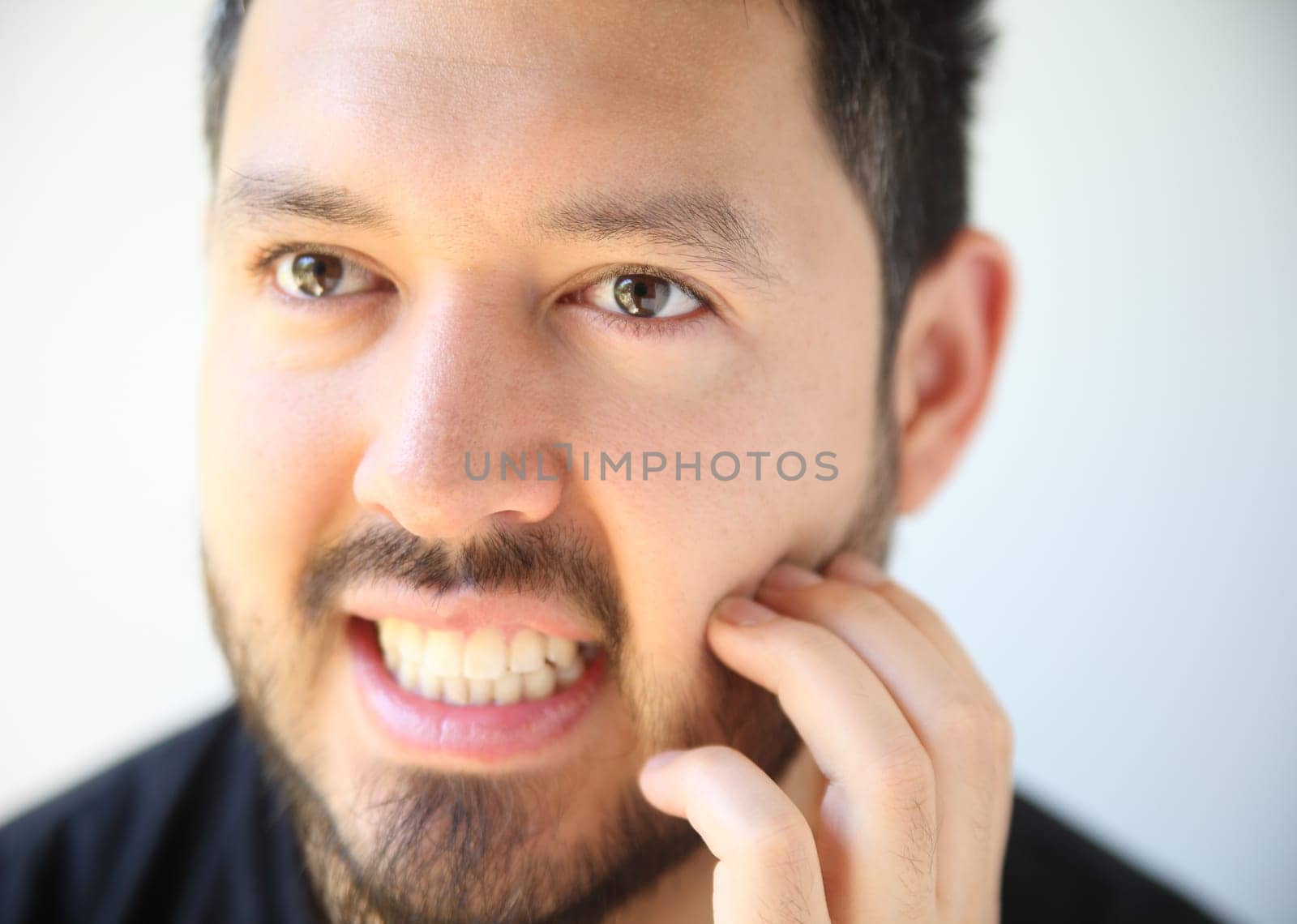 young man scratches his facial hair