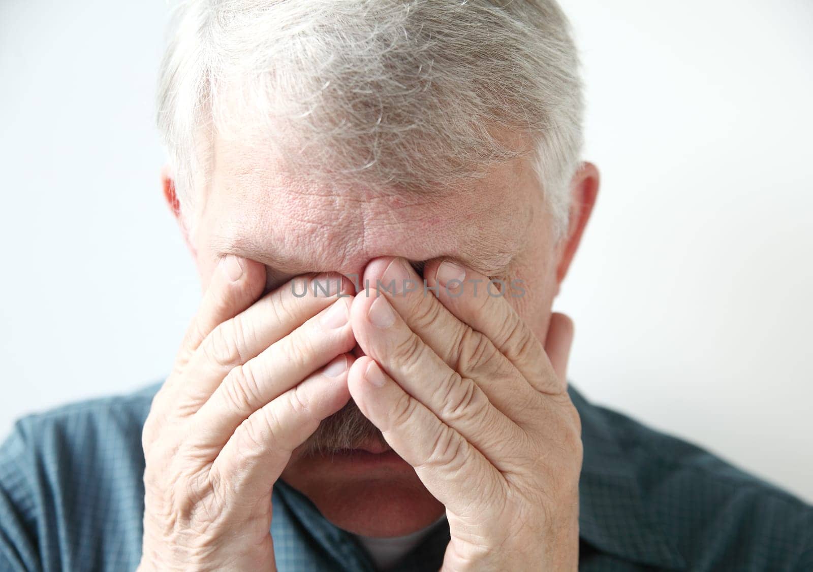 a senior with both hands over his eyes