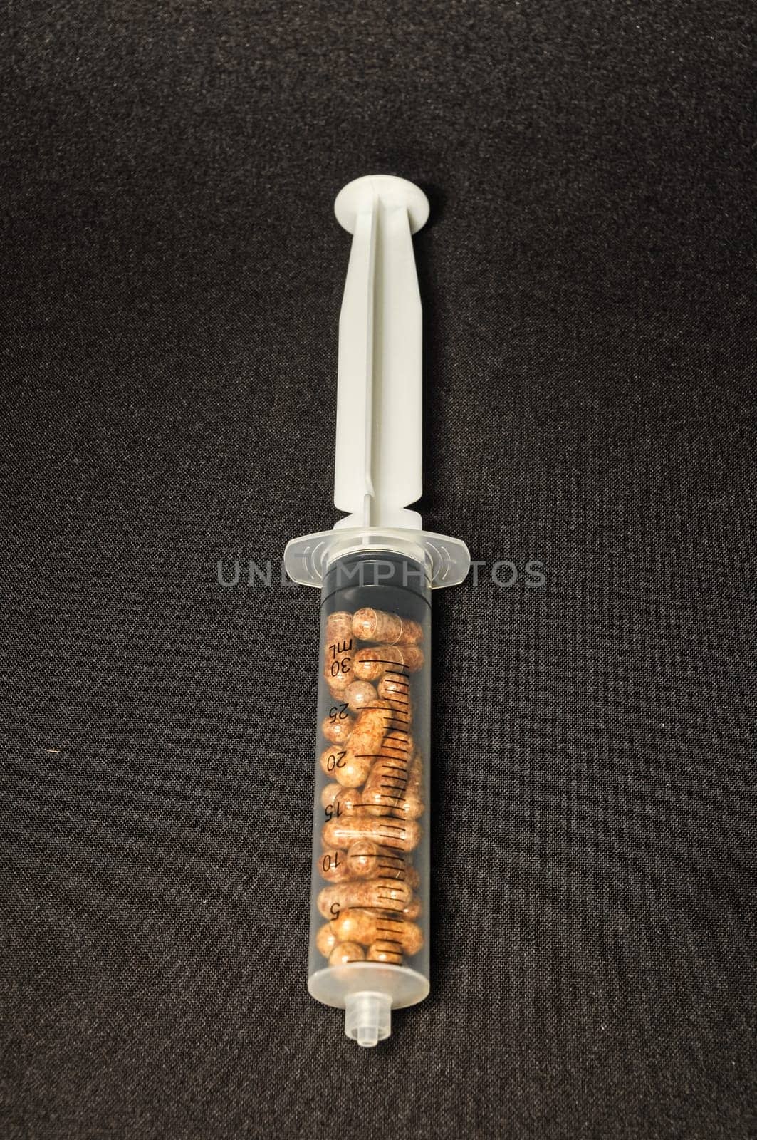 Medical Syringe Full of Pill Drugs on a Black Background