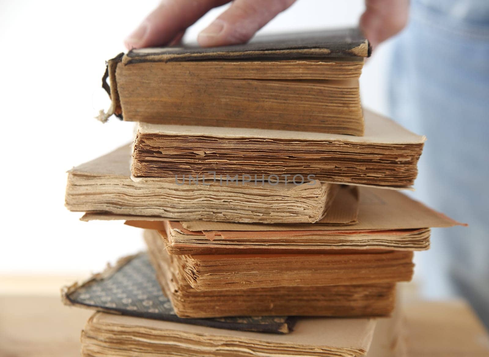 a man's hand on a stack of old books