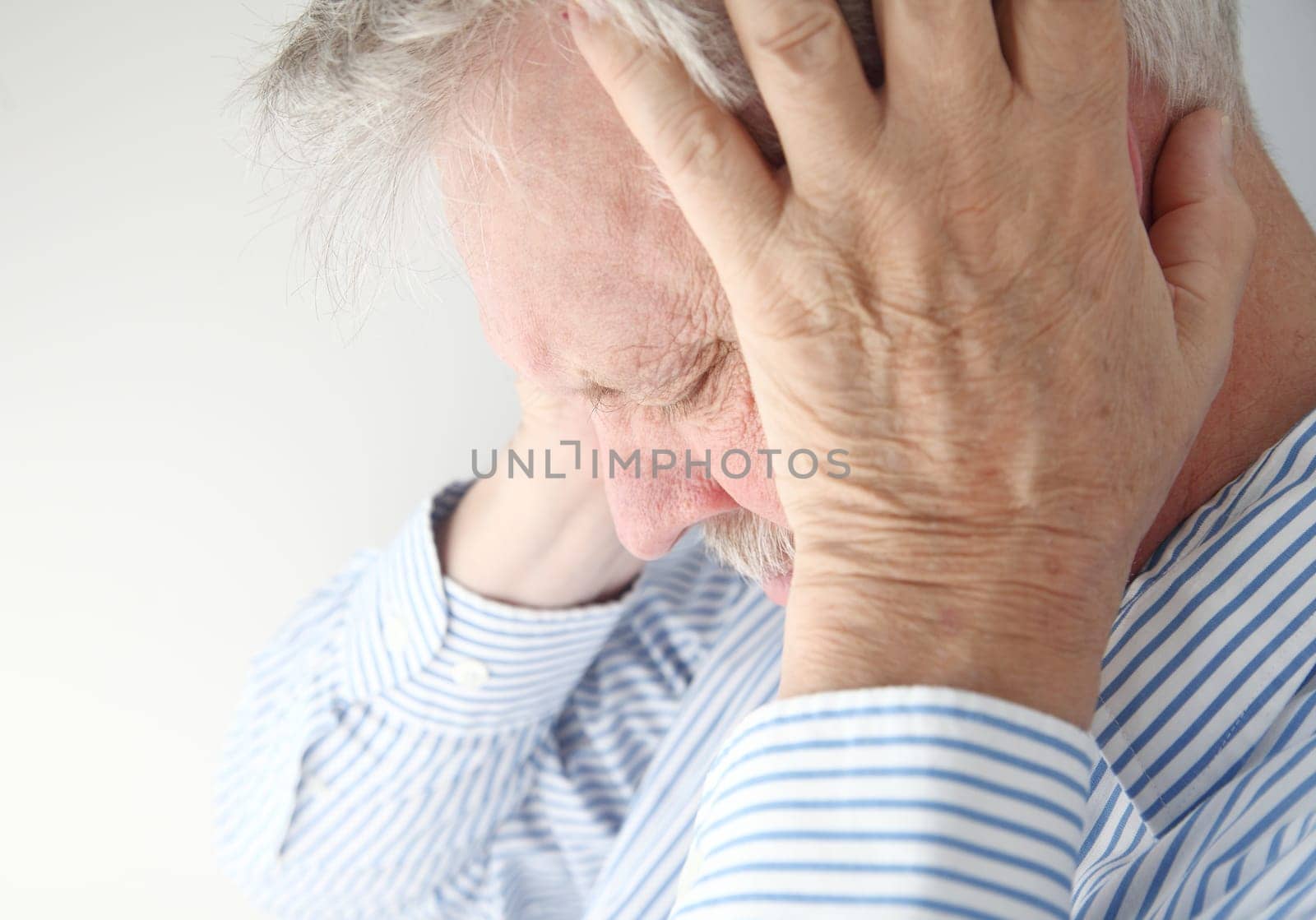 stressed older man holds his head in both hands